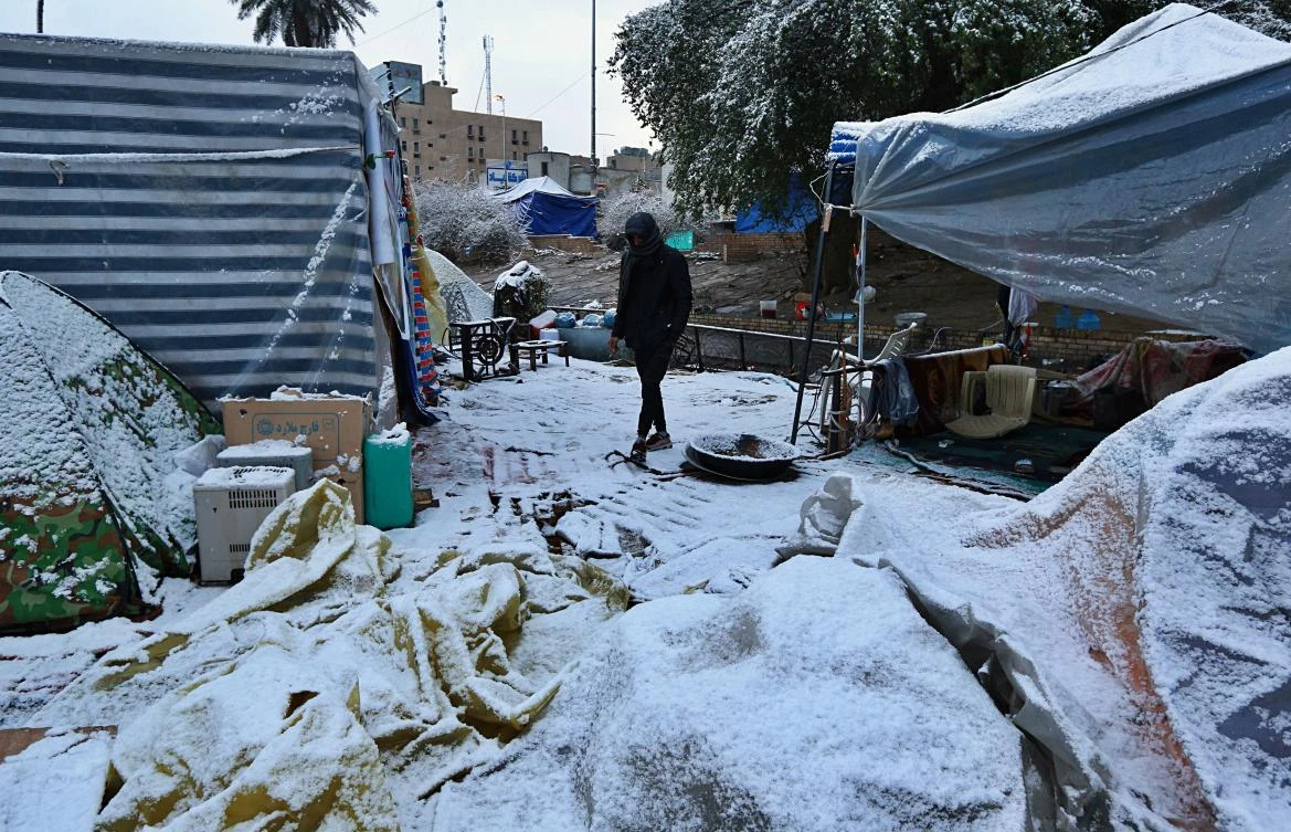 A protester walks in the snow in Tahrir Square during anti-government demonstrations in Baghdad. (AP)