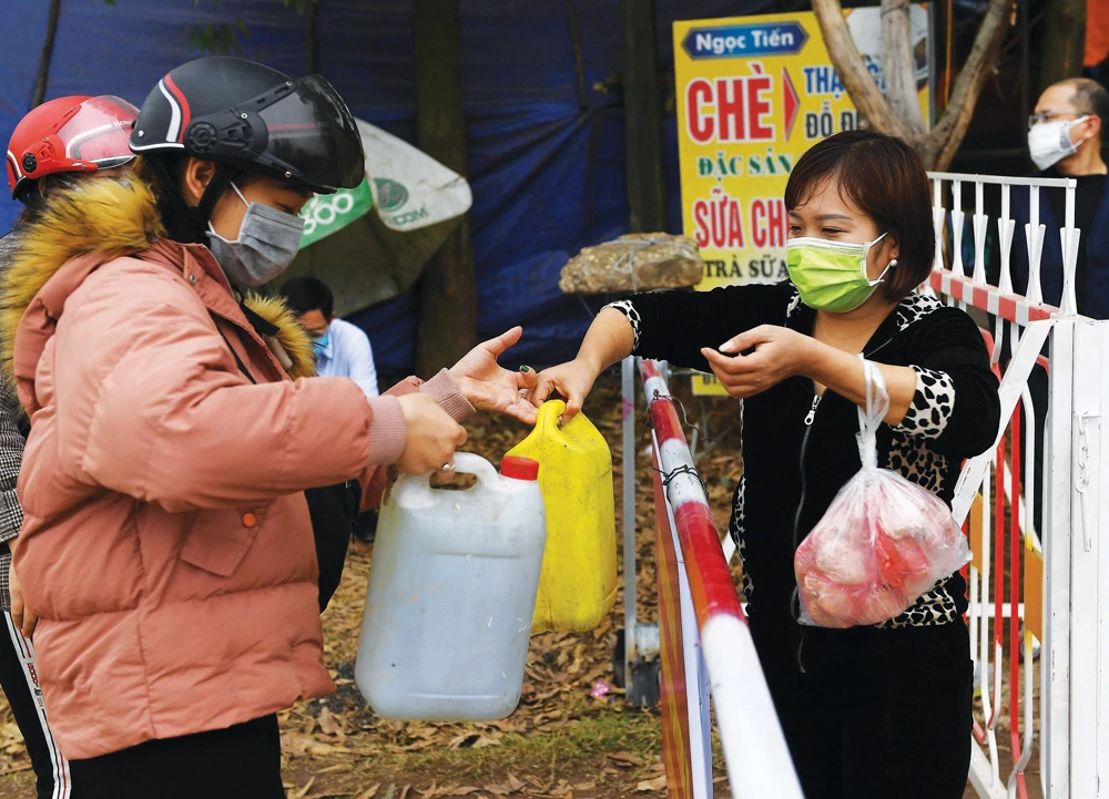 Local residents wearing protective face masks amid fears coronavirus pass containers of petrol across a checkpoint in Vietnam. (AFP)