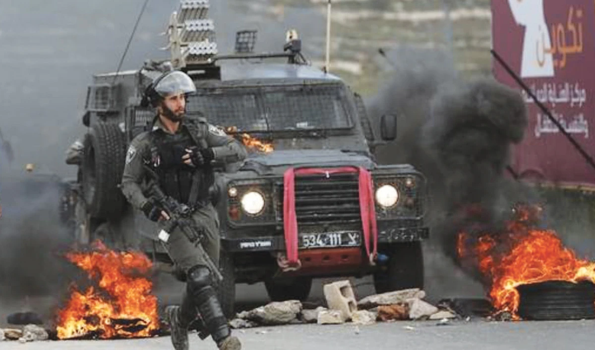 Israeli border policemen move away from a burning vehicle during clashes with Palestinians at a checkpoint in Beit El near the West Bank city of Ramallah. (AP)
