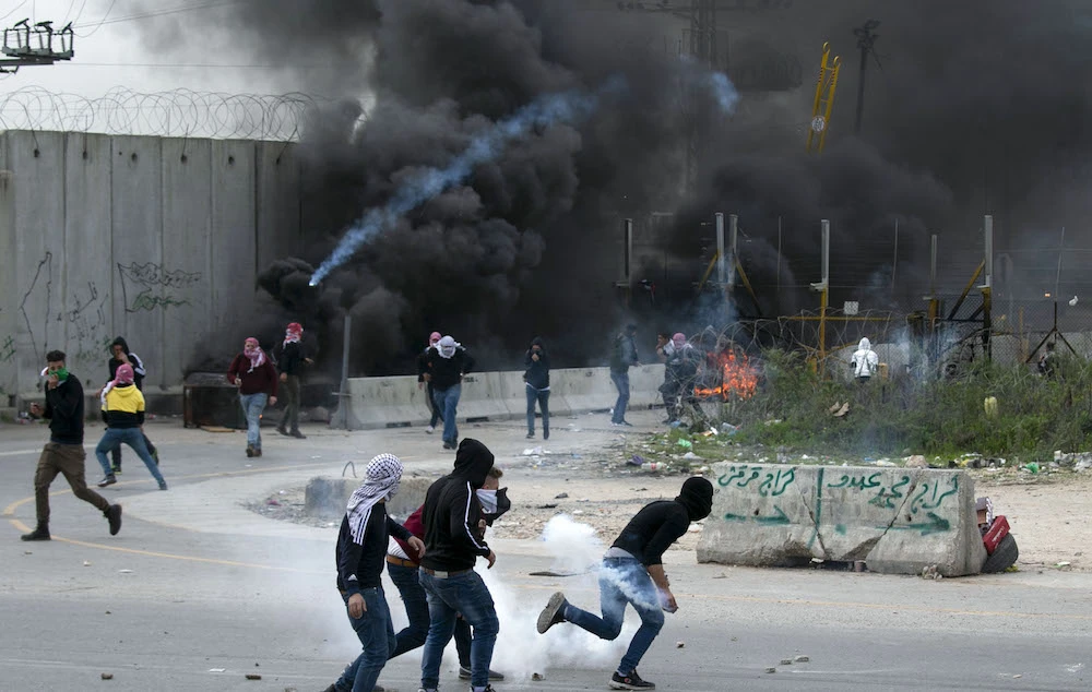 Palestinian demonstrators run for cover amid clashes with Israeli soldiers by the controversial separation barrier at the western entrance of the northern West Bank city of Tulkarem, on Feb. 18, 2020. (AFP)