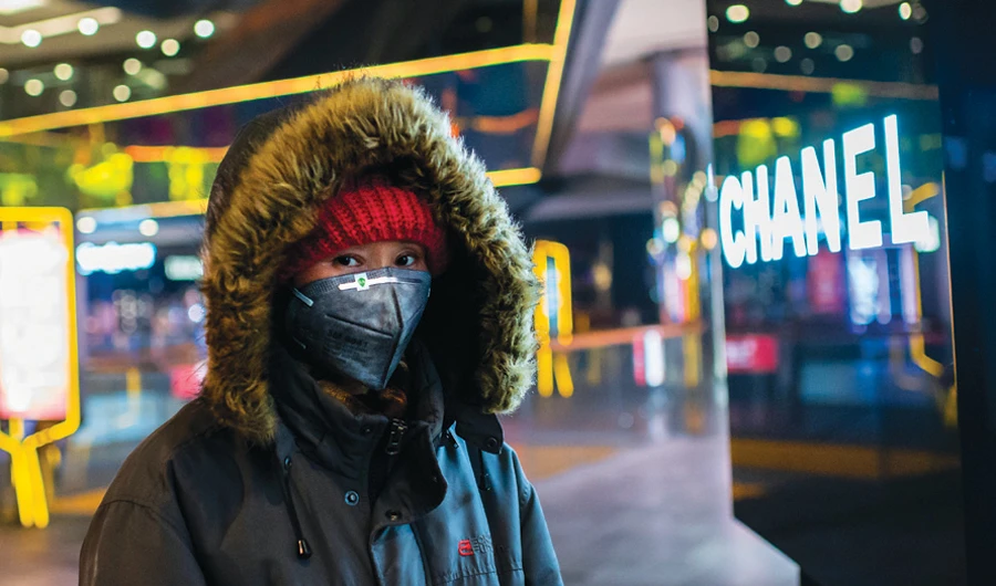A woman wearing a protective mask to help stop the spread of coronavirus walks at an empty shopping mall in the Sanlitun area in Beijing. (AFP/File)