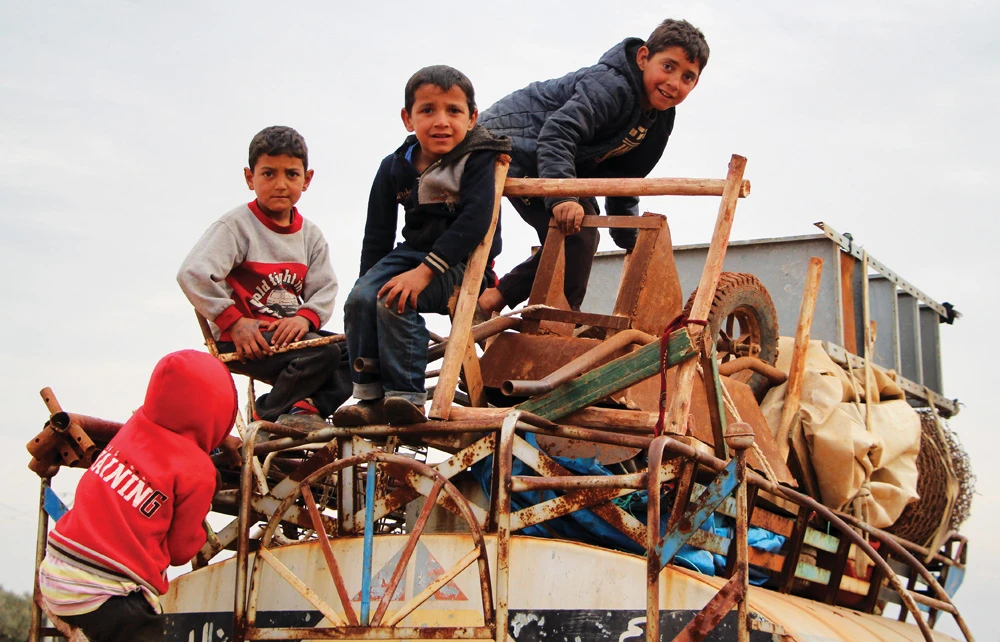 Children ride atop a water truck that is also loaded with furniture in the countryside of the village of Saharah in Syria's northern Aleppo province on Feb, 15, 2020. (Photo by Ibrahim Yasouf / AFP)