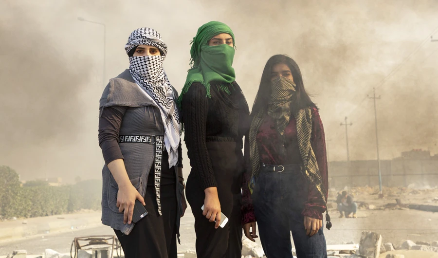 In this file photo taken on January 21, 2020, Iraqi protesters stand in the smoke of burning tires during an anti-government demonstration near the government building in the southern Iraqi city of Basra. (AFP)