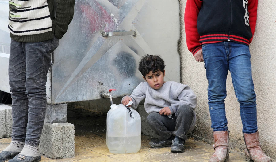 An internally displaced child fills a container with water, at an empty school and university compound used as shelter, in Azaz, Syria on Friday. (Reuters)