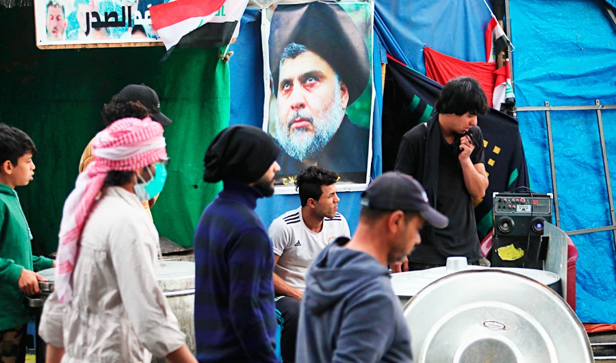 A poster of Shiite cleric Muqtada al-Sadr, right, is hung in Tahrir Square during ongoing anti-government protests in Baghdad, Iraq, Saturday, Feb. 22, 2020. (AP)