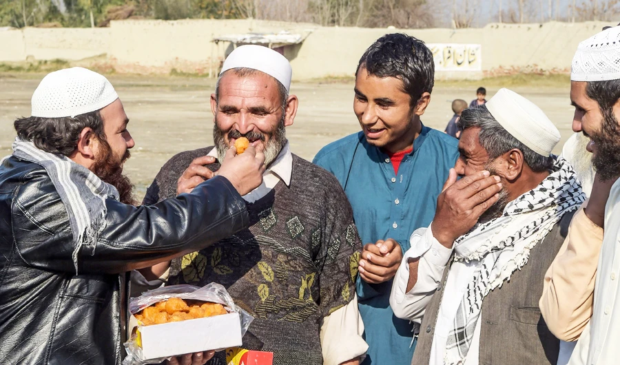 An Afghan refugee distributes sweets on the outskirts of Peshawar to celebrate the step toward peace agreed between Taliban, US and Afghan forces. (AFP)