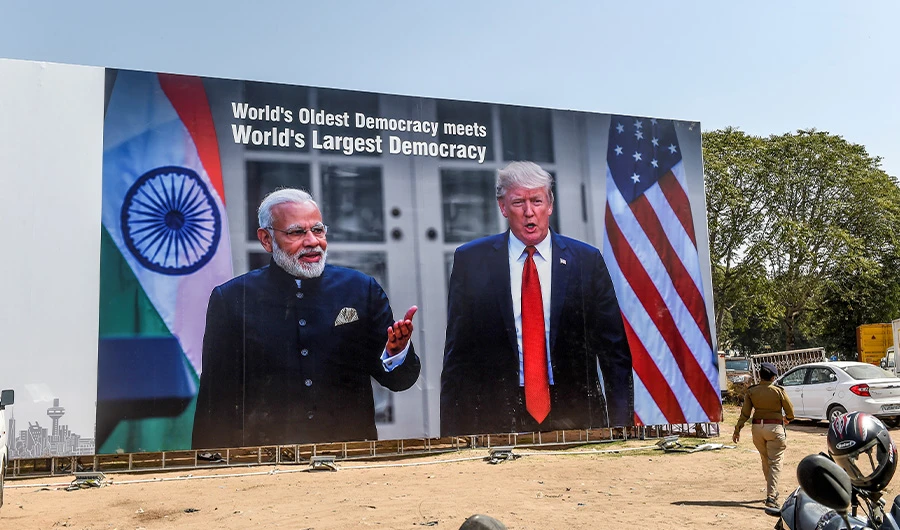 In this photo taken on February 22, 2020, a police personnel (R) walks past a billboard displaying pictures of India's Prime Minister Narendra Modi (L) and US President Donald Trump (R) near the Sardar Vallabhbhai Patel International Airport in Ahmedabad, ahead of US President Donald Trump's visit to India. (AFP)