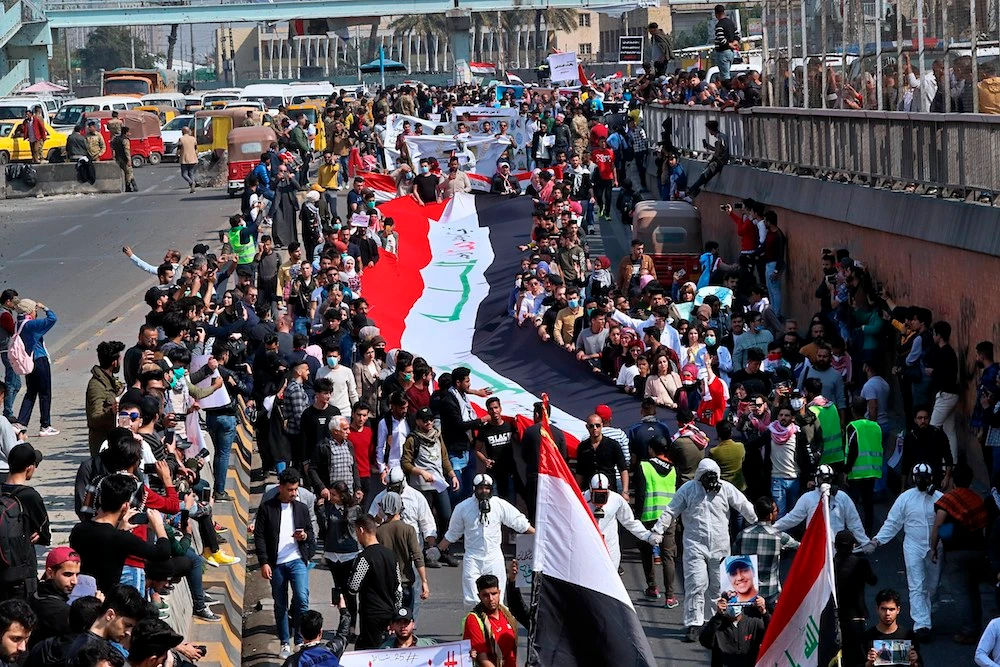 Image Caption : Students and other demonstrators hold national flags during ongoing anti-government protests, in Baghdad Sunday. (AP)