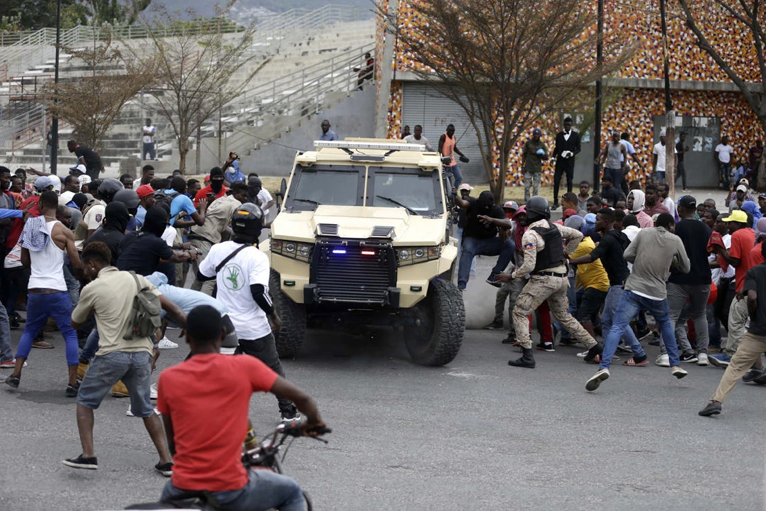 Armed off-duty police officers commandeer an armored vehicle to go shoot at army soldiers during a protest over police pay and working conditions, in Port-au-Prince, Haiti, on Feb. 23, 2020. (AP Photo/Dieu Nalio Chery)