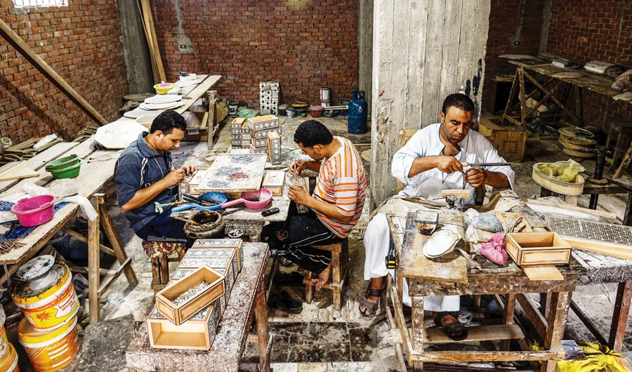 Egyptian craftsmen work on seashell wood inlays in Saqyat Al-Manqadi village. Furniture-makers are resisting moves to relocate to new industrial parks. (AFP)