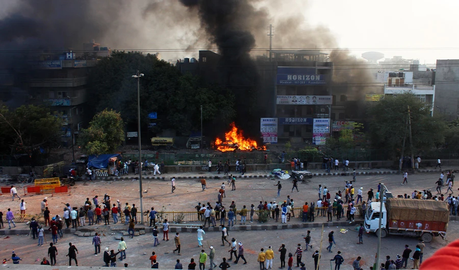 In this Monday, Feb. 24, 2020 photo, people watch car burn during clashes between hundreds of supporters and opponents of a new citizenship law in New Delhi, India. At least seven people, including a police officer, were killed and dozens were injured in the clashes against the law that provides fast-track naturalization for some foreign-born religious minorities but not Muslims, police said Tuesday. (AP)