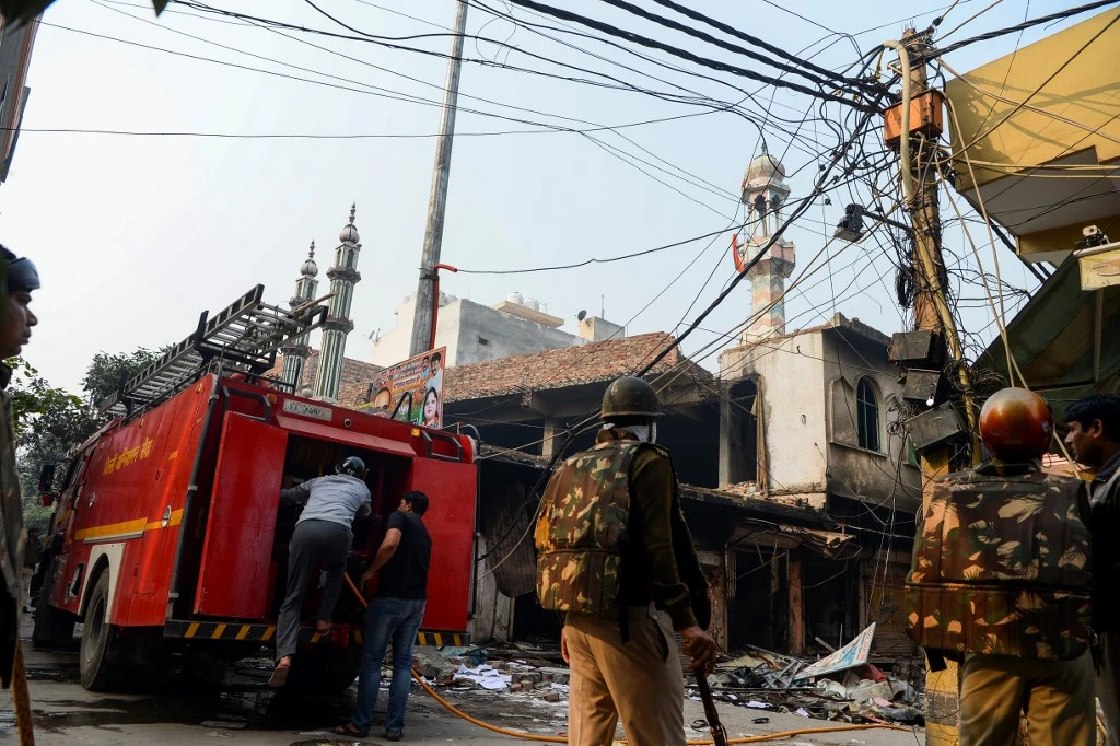 Security personnel stand guard near a burnt-out mosque and shops following clashes between people supporting and opposing a contentious amendment to India’s citizenship law, in New Delhi on February 26, 2020. (AFP)
