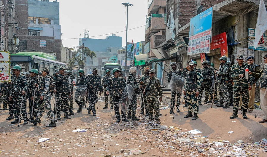 Security personnel stand guard near burnt-out and damaged shops following clashes between people supporting and opposing a contentious amendment to India's citizenship law, in New Delhi on February 26, 2020. (AFP)