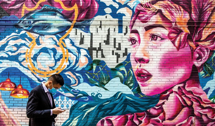 A man wearing a protective face mask, amid concerns over the spread of the COVID-19 novel coronavirus, walks past a mural in Hong Kong. (AFP)