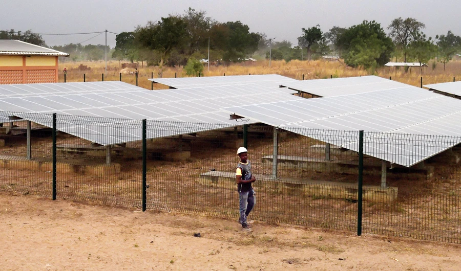 An engineer stands beside a fence protecting a solar panel installed in the Takpapieni village in Oti province, northern Togo. (AFP)