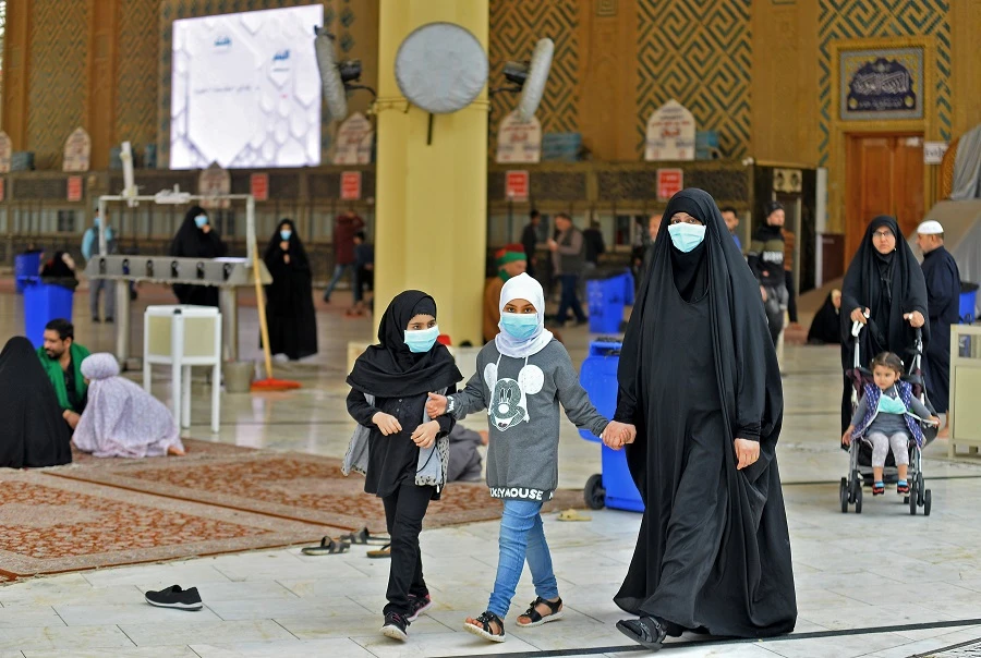 Pilgrims wearing masks walk through the courtyard of the shrine of Imam Ali on February 25, 2020 in the holy Iraqi central city of Najaf. (File/AFP)