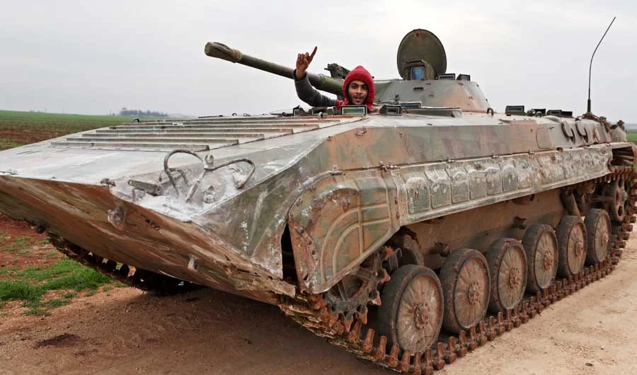 Turkish-backed Syrian opposition fighters drive down a road near the town Taftanaz in northeastern Idlib province, on Friday. (AFP)
