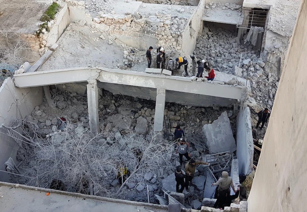 Residents and rescuers search for victims in the rubble of a building following pro-regime forces air strikes in the town of Binnish in Syria’s northwestern Idlib province, near the border with Turkey on February 25, 2020. (AFP)
