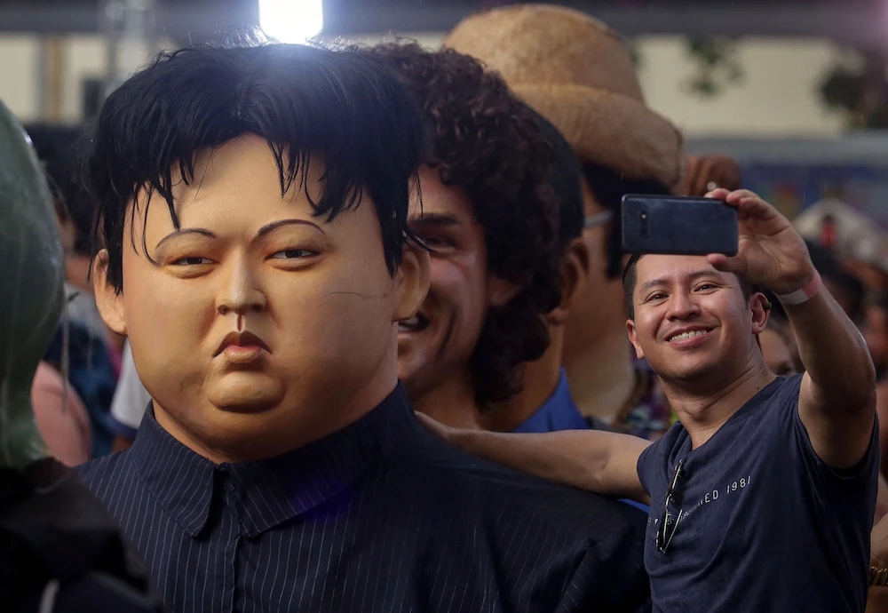 A man poses for a selfie next to giant puppet representing North Korea's leader Kim Jong-un during a traditional carnival parade through the streets of Recife in northeastern Brazil on February 25, 2020. Puppets of international and local personalities such as leaders Jair Bolsonaro of Brazil, US Donald Trump, China's Xi Jinping and North Korea's Kim Jong-un along with Swedish activist Greta Thunberg, late US singer Michael Jackson, late British David Bowie and others. (AFP)