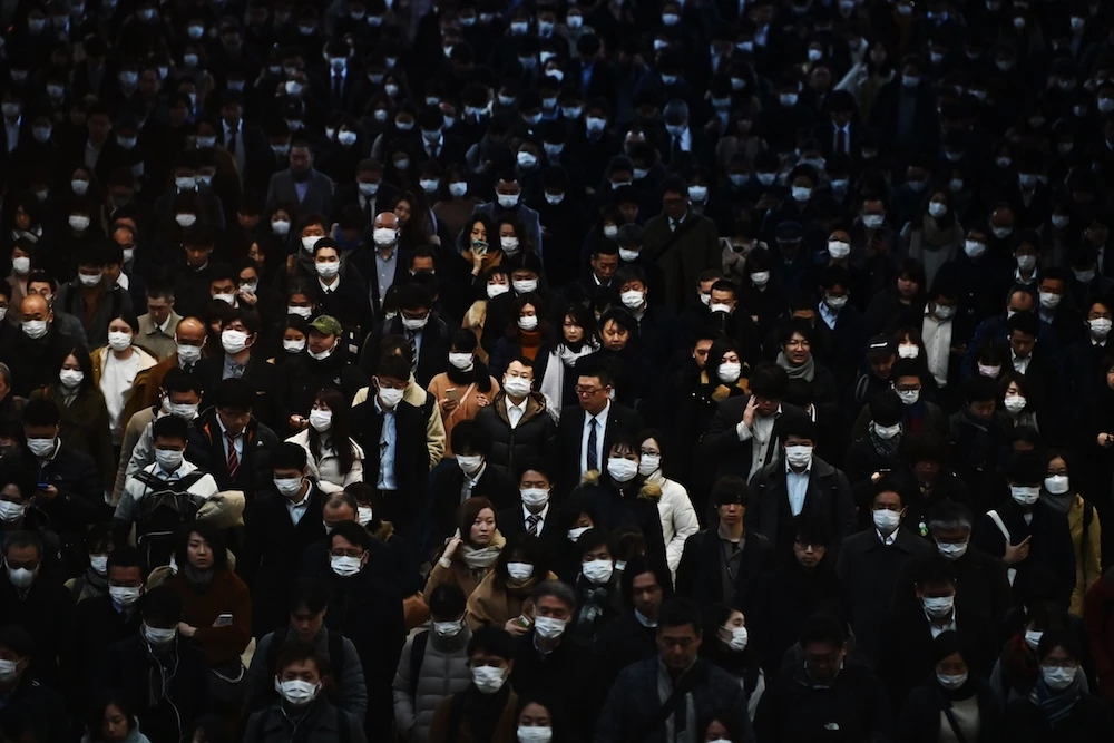 Mask-clad commuters make their way to work during morning rush hour at the Shinagawa train station in Tokyo on February 28, 2020. (AFP)