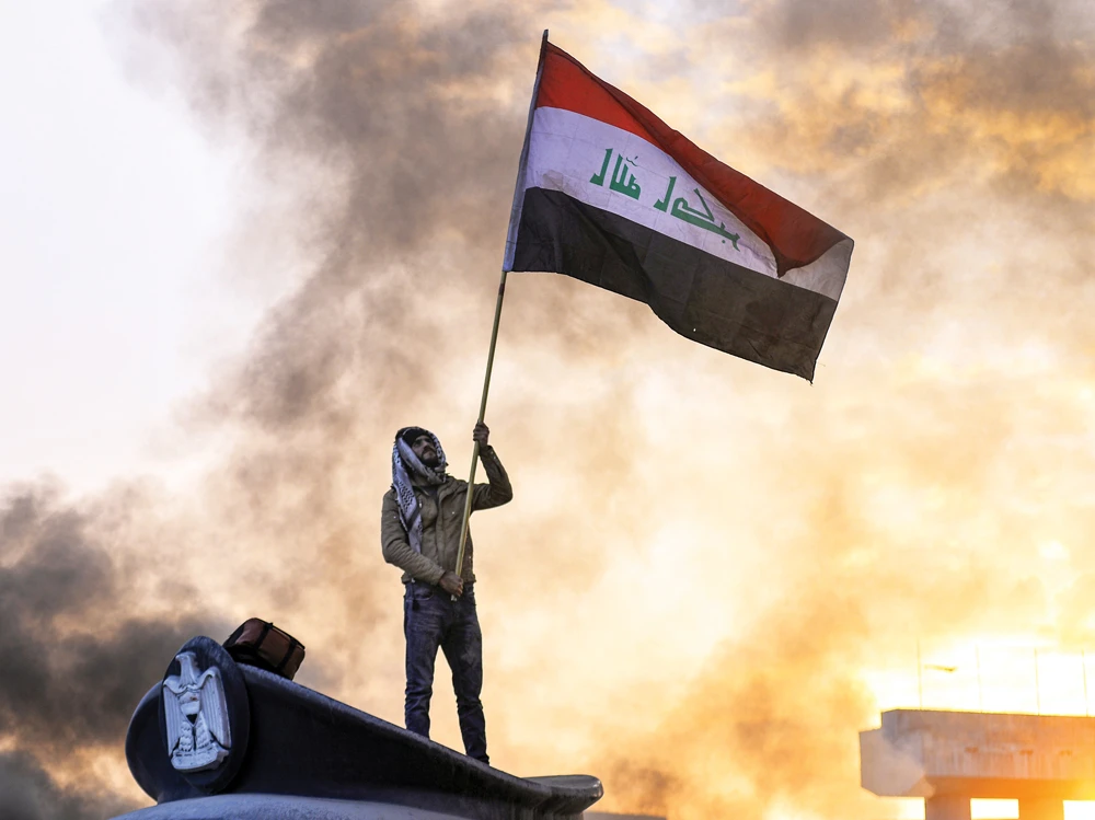 An anti- government protester waves a national flag during a demonstration in the central Iraqi holy shrine city of Najaf in January. (AFP)
