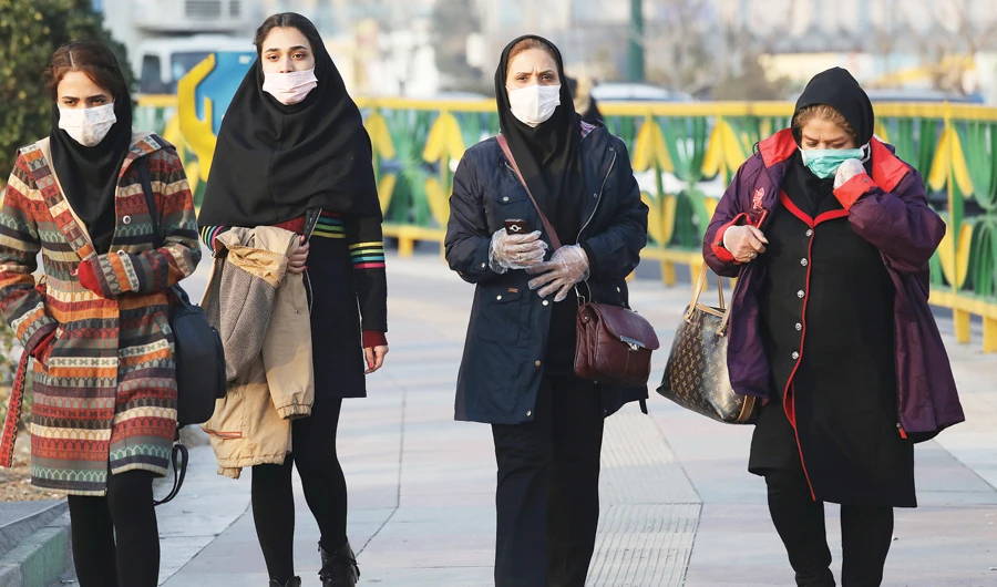 Iranian pedestrians wearing face masks walk on a sidewalk in western Tehran, as the number of confirmed cases of coronavirus spiked again on Sunday. (AP)