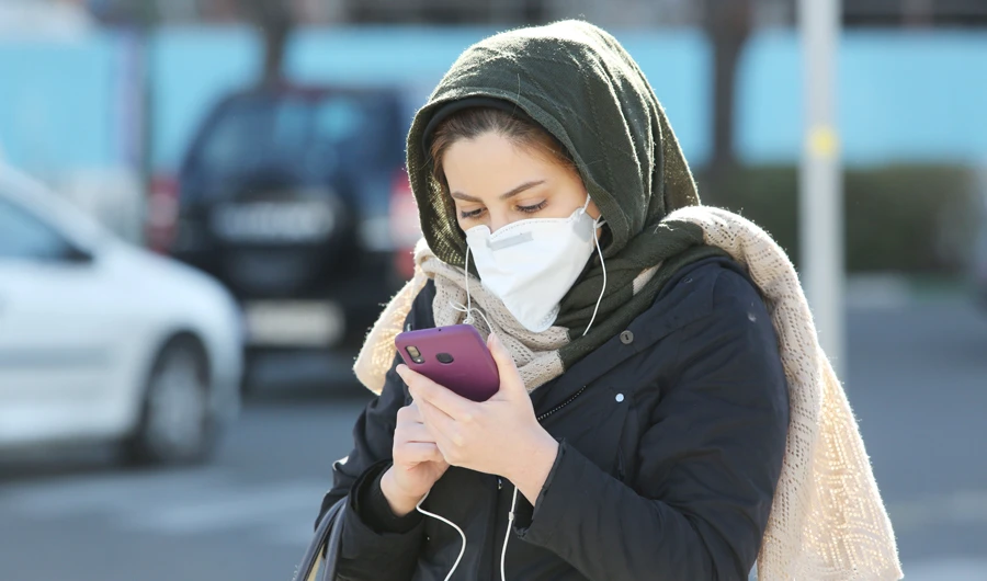An Iranian woman wearing a protective mask checks a message on her smart phone in the Iranian capital Tehran on March 2, 2020, following the COVID-19 illness outbreak, which Iran says has claimed 66 lives out of 1,501 cases of infection in the Islamic republic since February. (AFP)