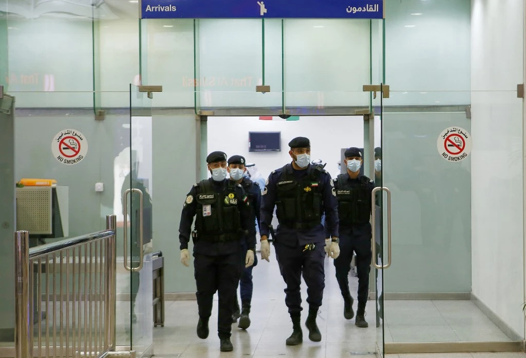 Kuwaiti policemen wearing protective masks wait at Sheikh Saad Airport in Kuwait City, on February 22, 2020, before transferring Kuwaitis arriving from Iran to a hospital to be tested for coronavirus. (File/AFP)