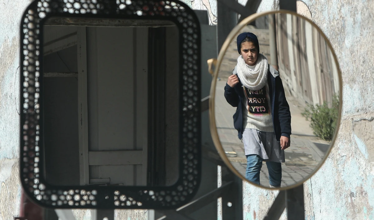A Palestinian schoolgirl is reflected in a mirror as she walks home from a United Nations-run school in Gaza City. (Reuters)