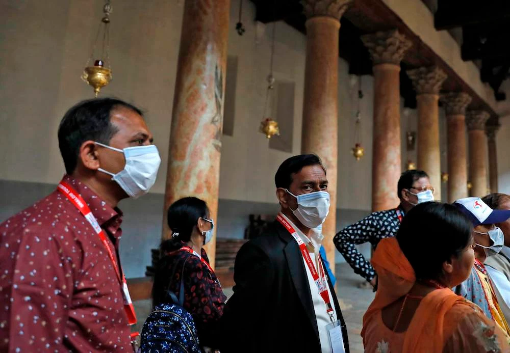 People wearing masks visit the Church of the Nativity in Bethlehem where the Palestinian health ministry called for local churches and mosques to close. (AFP)