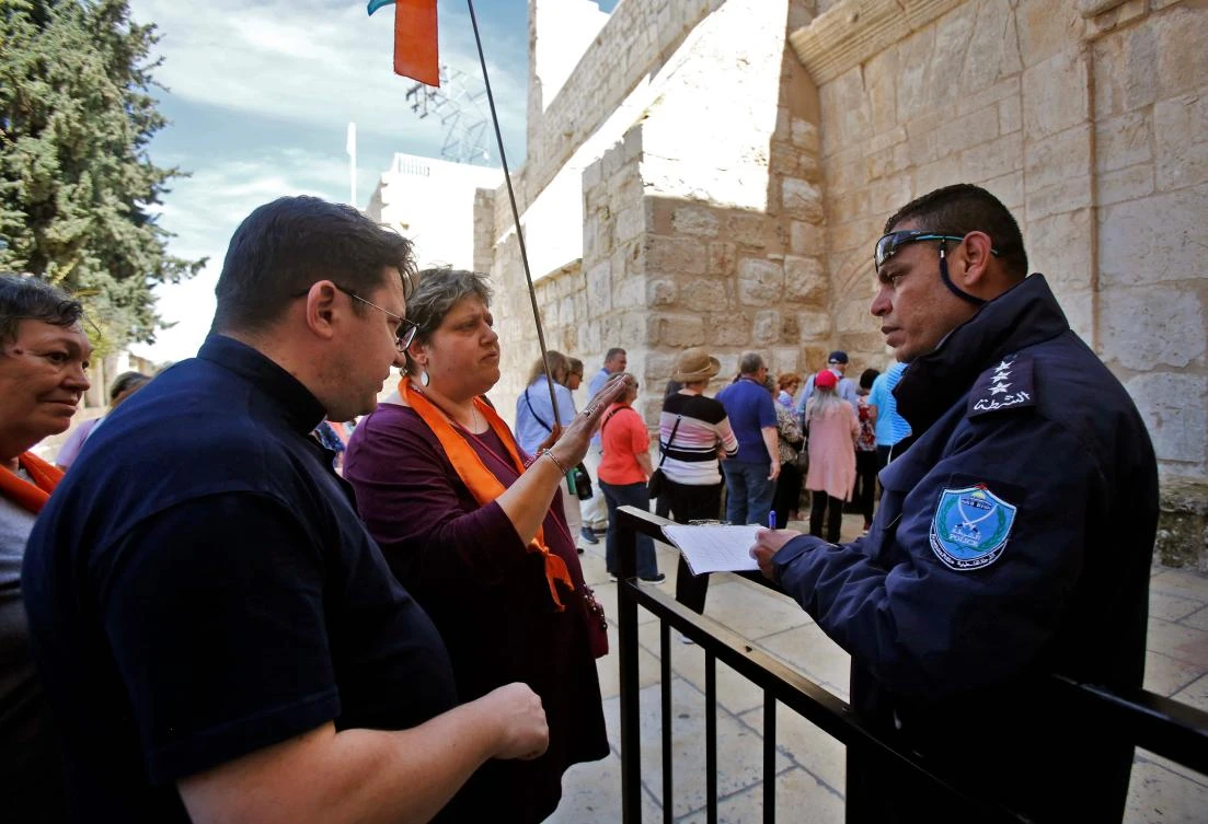 A Palestinian policeman registers tourists entering the Church of the Nativity, revered as the birthplace of Jesus Christ, in the West Bank city of Bethlehem on March 5, 2020. (AFP)