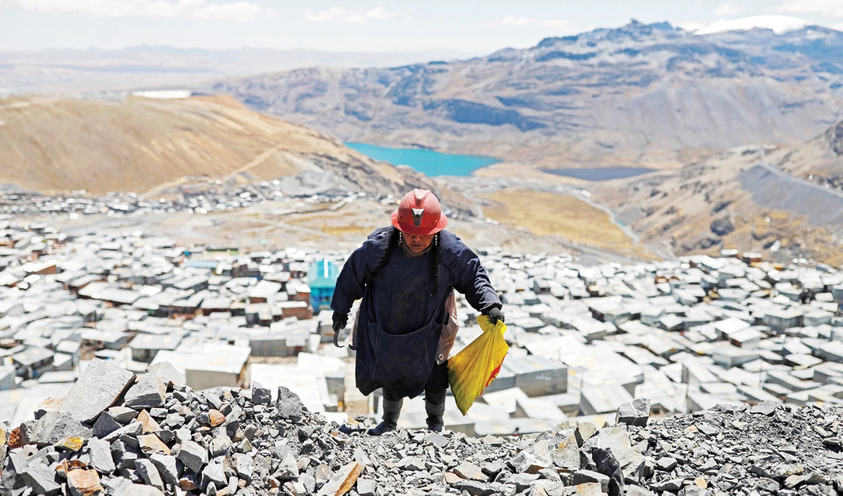 Eva Chura, a gold picker or “pallaquera,” strikes rocks that were discarded from a mine in search of gold above the Peruvian town of La Rinconada. (Reuters)