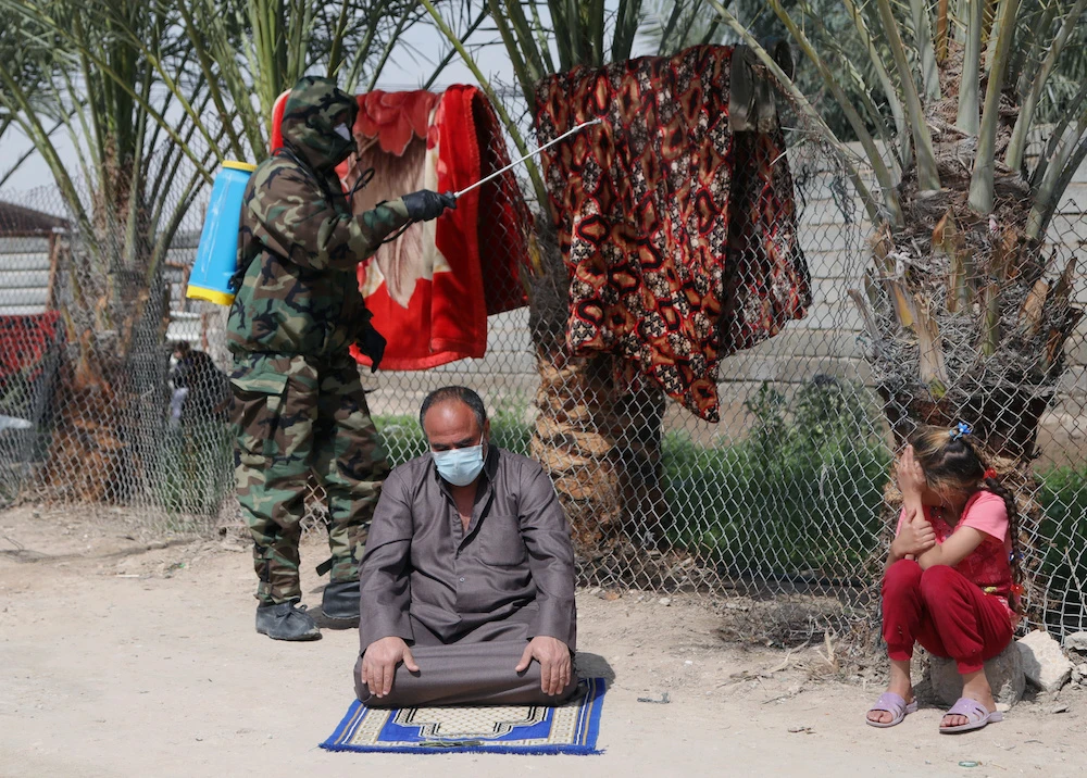 A member of the civil defense team sprays disinfectant to sanitize an area in the neighbourhood of the house of the person who was diagnosed with coronavirus and died, in Kerbala, Iraq. (Reuters)