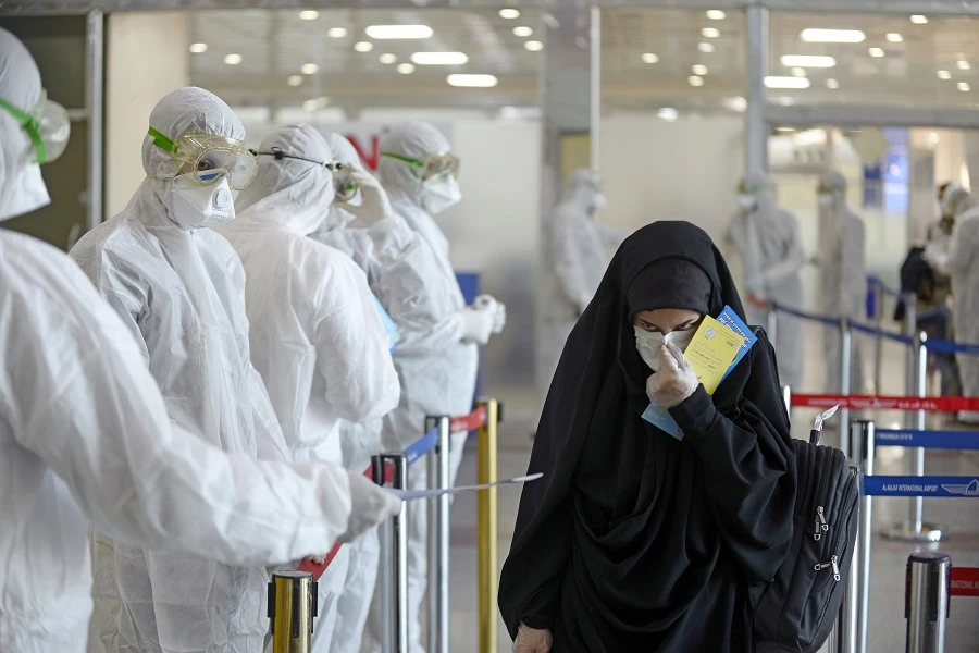 Medical staff in protective gear distribute information sheets to Iraqi passengers returning from Iran at Najaf International Airport. (AFP)