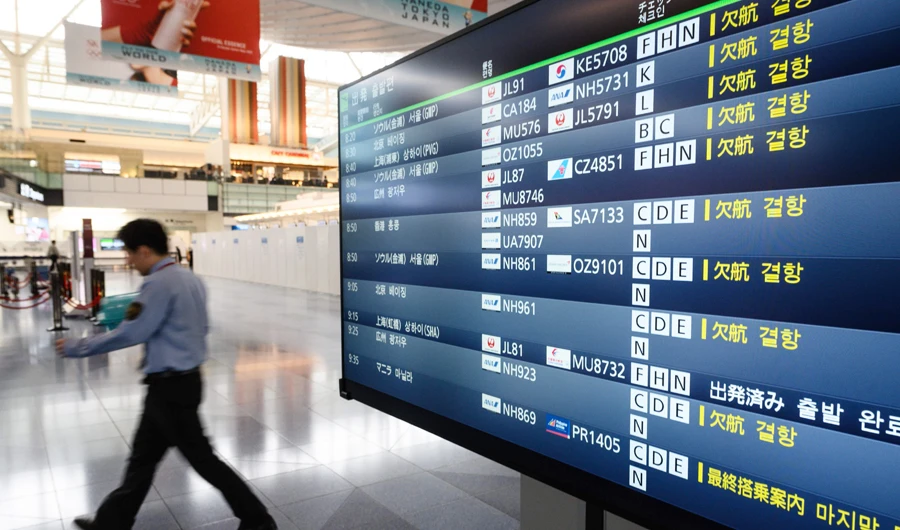 A man walks past a departure board showing cancelled flights at Tokyo's Haneda Airport on March 10, 2020. (AFP)