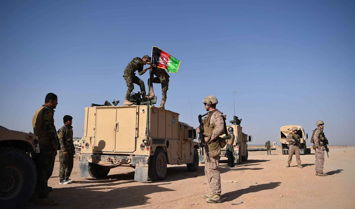 In this file photo, a US Marine looks on as Afghan National Army soldiers raise the Afghan National flag on an armed vehicle during a training exercise in Lashkar Gah in Helmand province on Aug. 28, 2017. (AFP)
