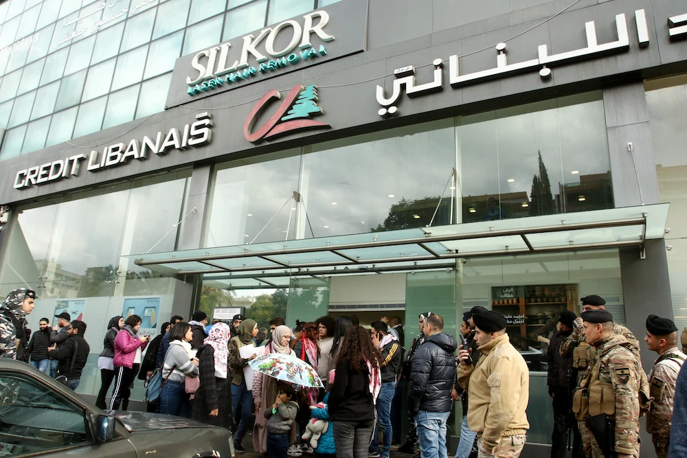 Lebanese protesters gather in front of a bank in the southern city of Sidon (Saida) to protest against nationwide imposed restrictions on dollar withdrawals and transfers abroad in an attempt to conserve dwindling foreign currency reserves. (File/AFP)