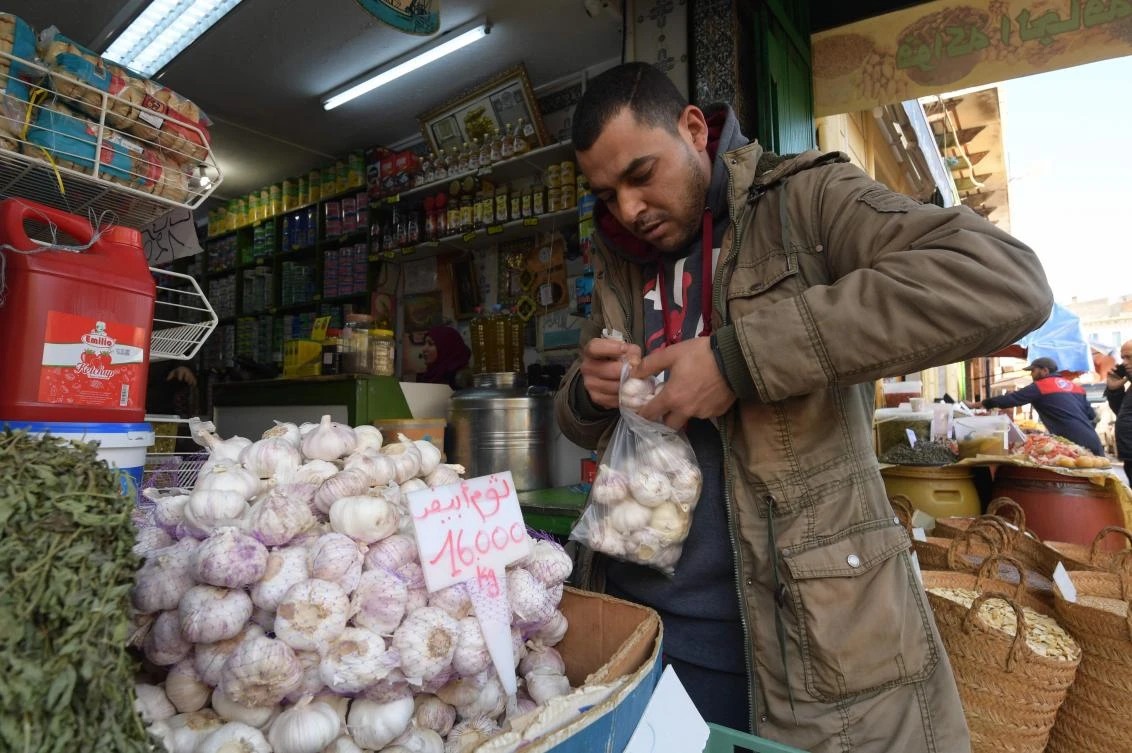 A costumer buys garlic bulbs at a central market in Tunis on March 12, 2020. The price of garlic has skyrocketed in recent days in Tunisia as consumers rush to buy it in the hope that its antimicrobial properties will help to protect against coronavirus. (AFP)