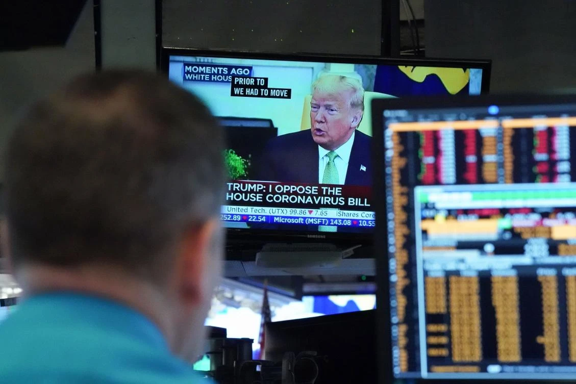 President Donald Trump speaks on television from the White House as traders work on the floor of the New York Stock Exchange. (AFP)