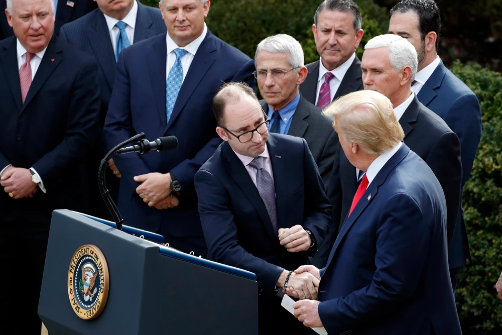President Donald Trump shakes hands with Richard Ashworth, president of Walgreens, during a news conference about the coronavirus in the Rose Garden at the White House on March 13, 2020, in Washington. (AP Photo/Alex Brandon)