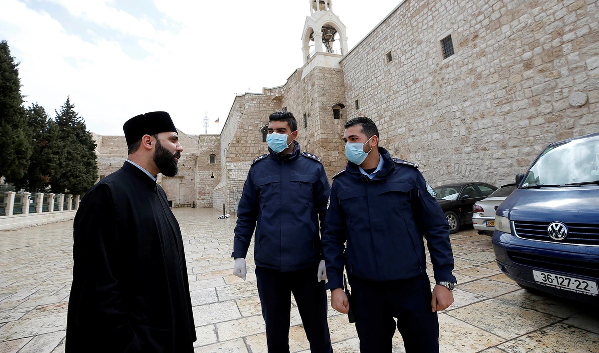 In this file photo, Palestinian police officers stand guard outside the Church of the Nativity that was closed as a preventive measure against the coronavirus in the occupied West Bank on March 6, 2020. (REUTERS)