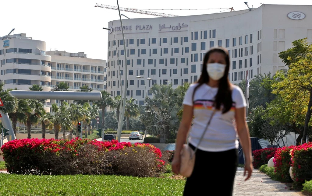 A woman wearing a protective mask walks outside the Crowne Plaza hotel at Yas Island Abu Dhabi on February 28, 2020. (File/AFP)