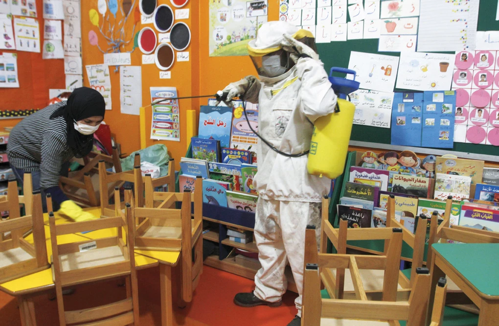 Workers spray a classroom in a school in Lebanon, left. A school closure notice, above, and (below) an empty classroom in the Netherlands. (AFP)