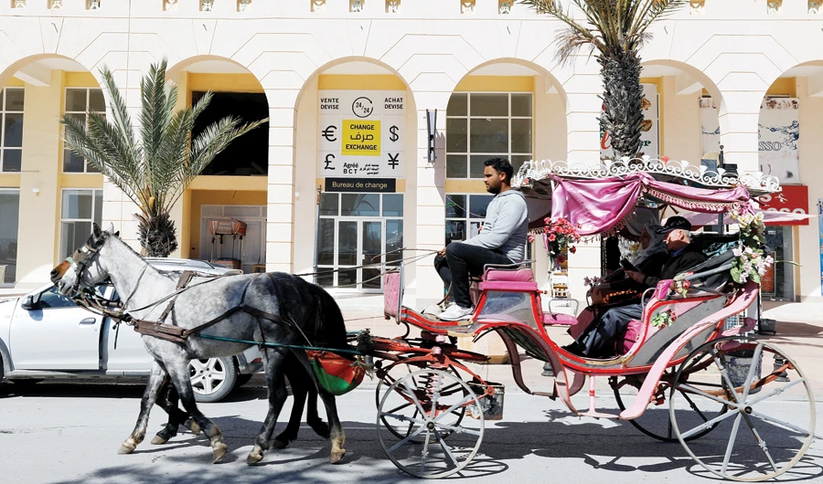 Tourists ride on a horse cart near a currency exchange in Hammamet, Tunisia. (Reuters)