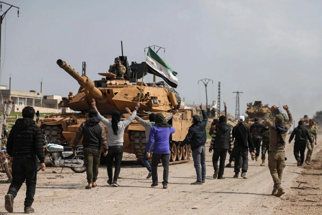 Protesters surround a Turkish military M60T tank as they attempt to block traffic on the M4 highway, which links the northern Syrian provinces of Aleppo and Latakia. (AFP file photo)