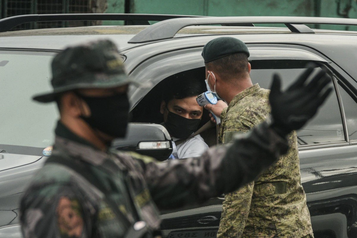A soldier checks the temperature of a motorist at a checkpoint on the outskirts of Manila. (AFP)