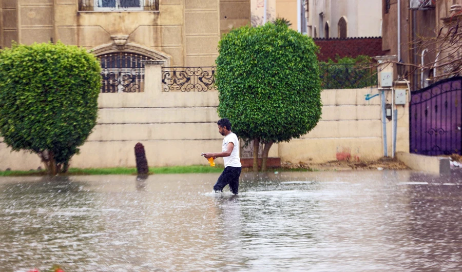 A man walks through rain in a heavily flooded street in the New Cairo suburb of the Egyptian capital on March 12, 2020 amidst a heavy rain storm. (AFP)
