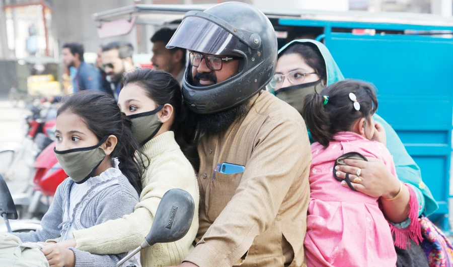 A Pakistani family wears face masks to help prevent exposure to the new coronavirus as they travel on a motorbike in Lahore on Monday. (AP)