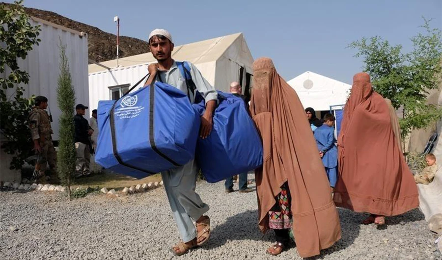 An Afghan family, carries bundles of supplies at a humanitarian aid station in Torkham, Afghanistan, October 22, 2016. (Reuters)