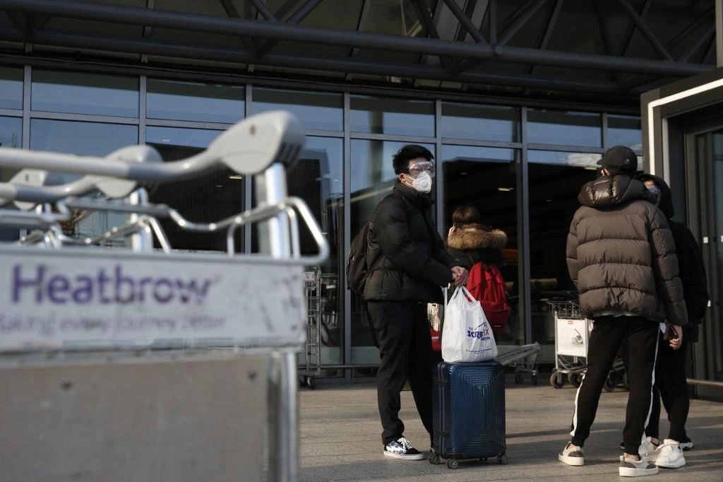 A traveler wearing a mask waits oustside an Heathrow’s airport terminal on March 16, 2020. (AFP)